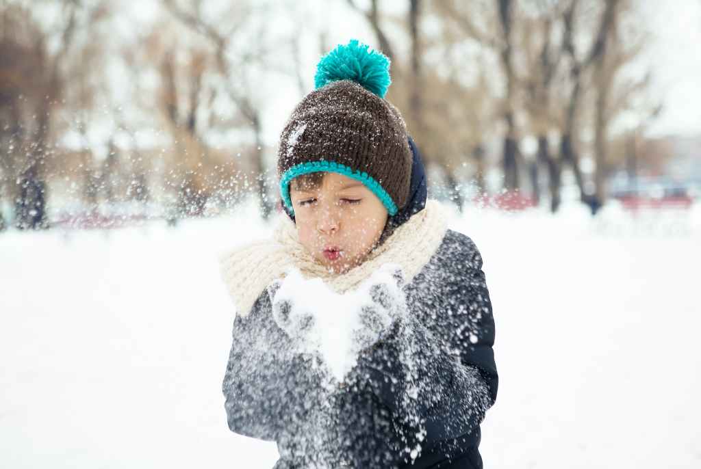 Excited kid playing in the snow, exploring the wonders of winter for a snowy science experiment. Spark curiosity with Our Days Calendar. #OurDaysSnowScience