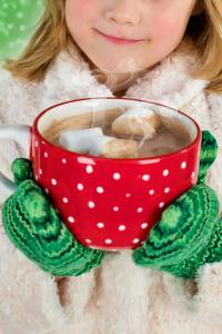 Young child with a beaming smile, holding a steaming cup of hot cocoa adorned with marshmallows. Enjoying winter warmth and family moments with Our Days Calendar. #OurDaysCocoaJoy